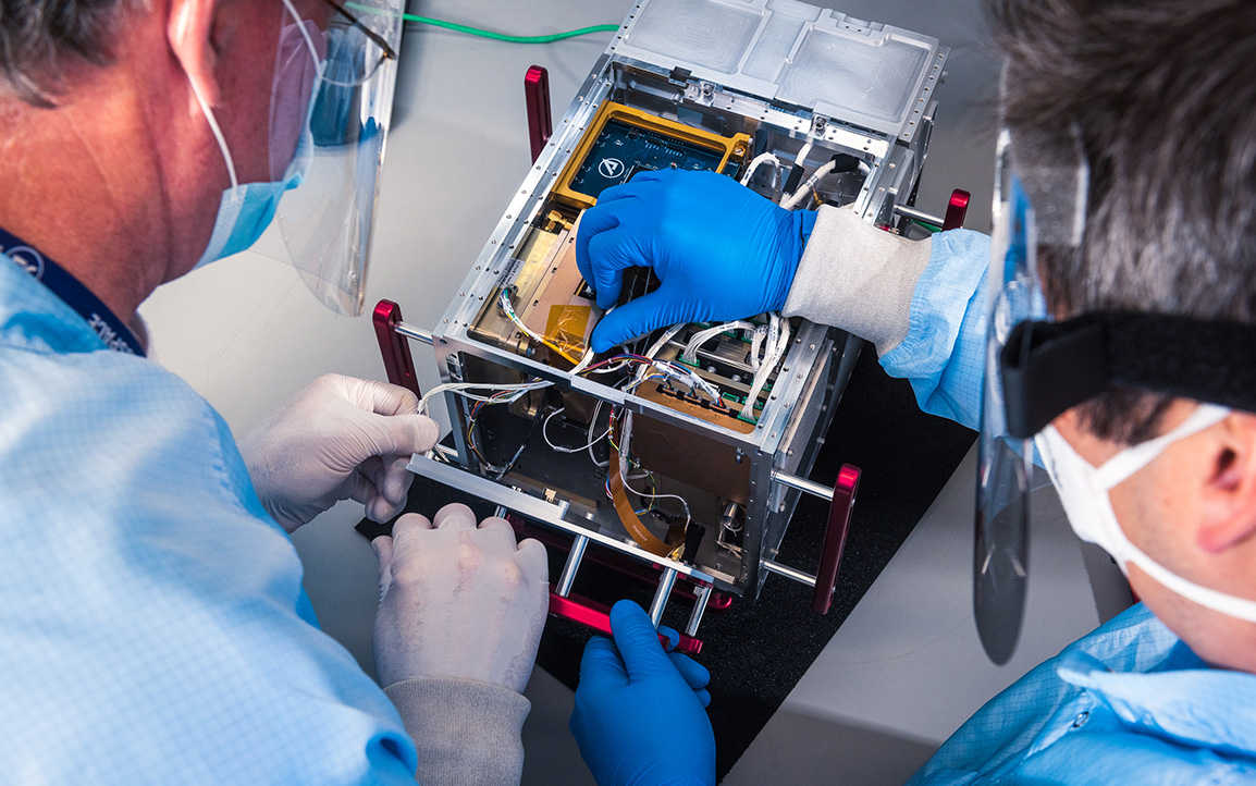 Image of scientists work on satellite payload