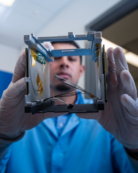 A lab technician holding the frame of AeroCube 10