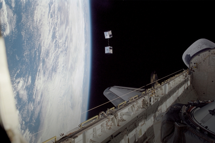 Picture of smallsat's teathered together being release from the space shuttle in space
