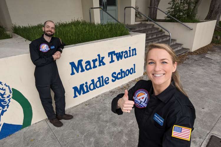 Aerospace team in front of Mark Twain Middle School sign.