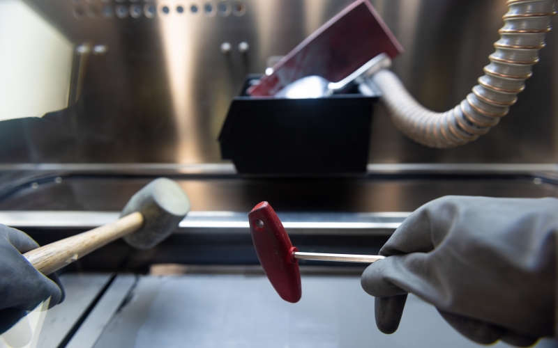 A technician clears leftover AM material from printing area.