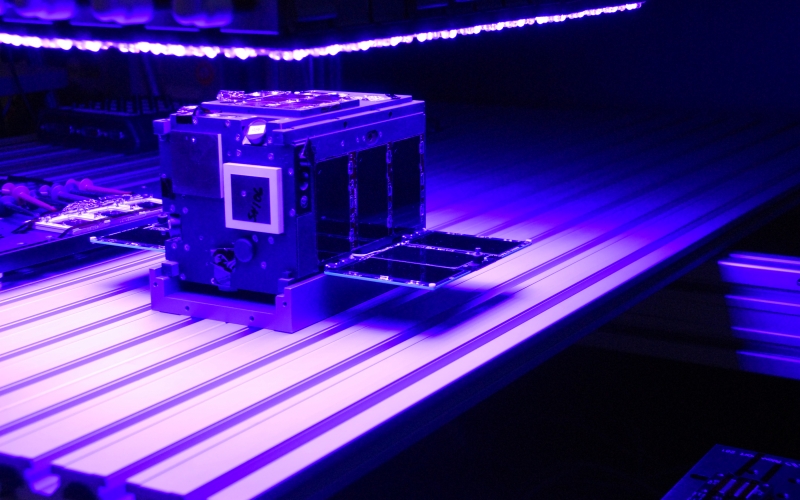 AeroCube-10 in purple light being tested.