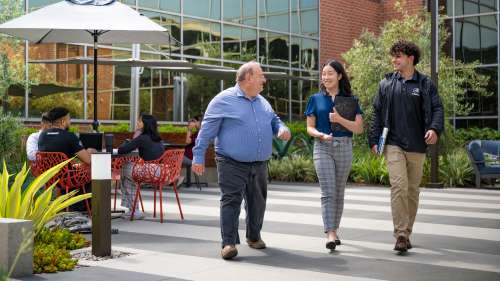 Three people walking through Aerospace campus, talking.