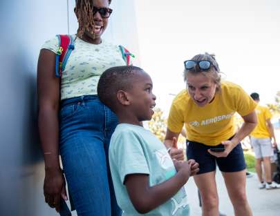 A child, a parent and an Aerospace volunteer speaking outside at Rocket Fever event.