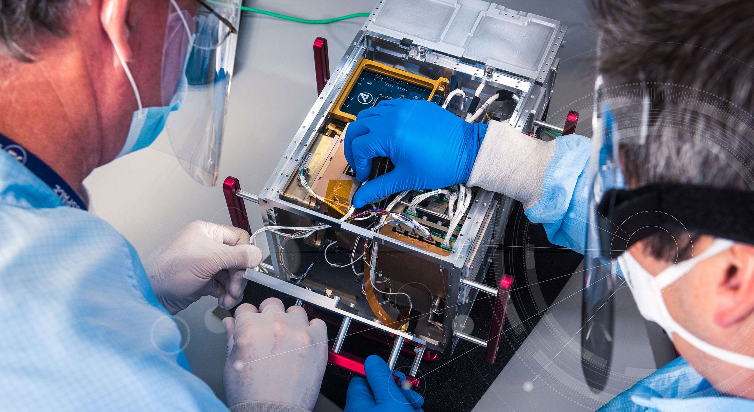 Image of Aerospace engineers working on electronics integration into a cubesat.